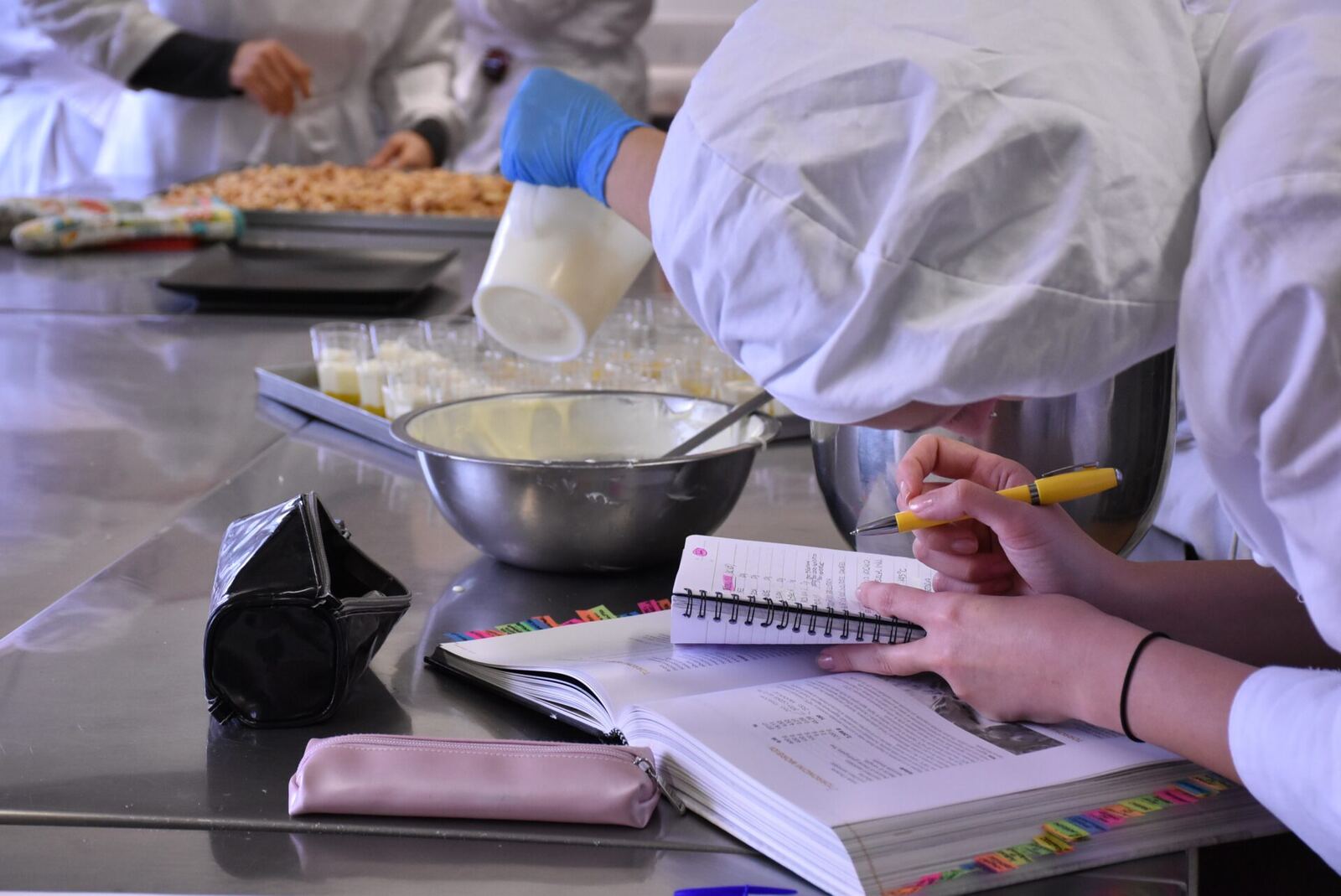 Allieva studia il ricettario mentre in laboratorio si prepara la crema